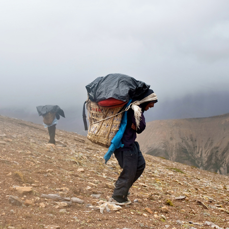 DOLPO, NEPAL - SEPTEMBER 12: Porters carrying heavy load across Himalayan pass on September 12, 2011 in Upper Dolpo restricted area, Nepalのeditorial素材