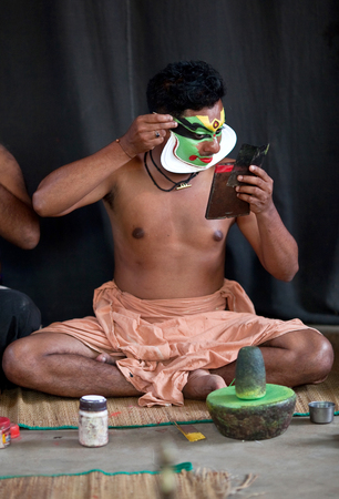 VARKALA, INDIA - FEBRUARY 10, 2010: Kathakali actor applies make-up before the evening performance in Varkala, India. Kathakali - the classical dance-drama of Kerala based on Indian mythology.のeditorial素材
