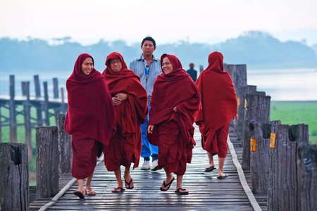 Buddhist monks walking on famous U-Bein teak bridge on January 13, 2011 in Amarapura, Myanmar.のeditorial素材