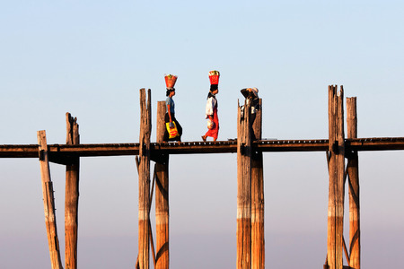 Women walking on famous U-Bein teak bridge on January 13, 2011 in Amarapura, Myanmar.のeditorial素材