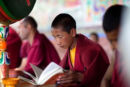LADAKH, INDIA - JUNE 11, 2012: Young Tibetan Buddhist novice monk praying in Thiksey gompa (Buddhist monastery) of the Yellow Hat (Gelugpa sect).のeditorial素材