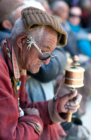 Man with prayer wheel praying in Lamayuru Gompa during Yuru Kabgyat festival at Lamayuru Gompa on...