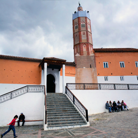 CHEFCHAOUEN, MOROCCO - JANUARY 2, 2014: People resting on the square nearby Grand Mosque in Medina of Chefchaouen, Morocco. Noteworthy for its unusual octagonal tower, the Grande Mosque was built in the 15th century by the son of the town's founder, Ali bのeditorial素材