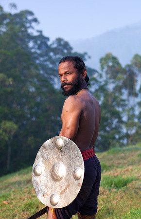 Indian fighter with sword and shield performing Kalaripayattu marital art demonstration in Kerala, South Indiaの写真素材