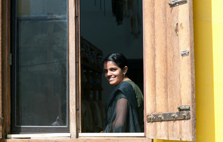 COCHIN, INDIA - JANUARY 21, 2016: Smiling beautiful Indian girl in sari  looking outdoors through a window in Fort Cochin, Kerala, South Indiaのeditorial素材