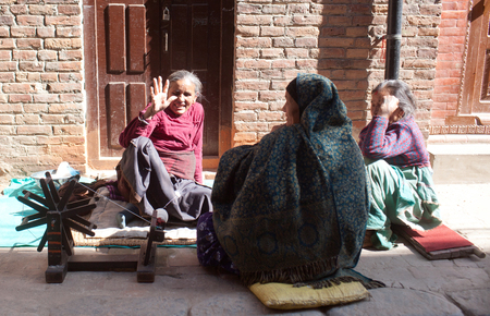 BHAKTAPUR, NEPAL - JANUARY 23, 2017: Nepalese women with spinning-wheel chat together at Durbar squareのeditorial素材