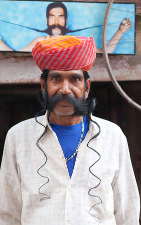 BIKANER, INDIA - JANUARY 11, 2019: Indian man presenting his famous long mustache during Camel Festival in Rajasthan. Untying the knot reveals about a meter long mustache on each side.のeditorial素材