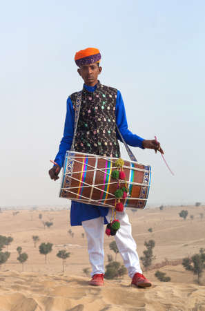 BIKANER, INDIA - JANUARY 12, 2019: Young Indian drummer in traditional clothes performing during Camel festival in Thar desert in Rajasthan state.のeditorial素材