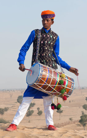 BIKANER, INDIA - JANUARY 12, 2019: Indian drummer in traditional clothes performing during Camel festival in Thar desert in Rajasthan state.のeditorial素材