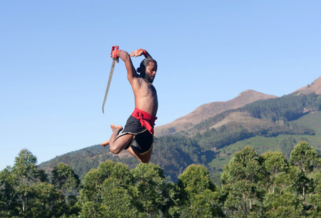 Indian fighter with sword jumping up during Kalaripayattu Marital art demonstration in Kerala, South...