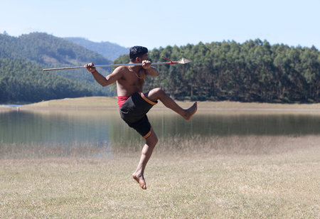 Indian fighter with lance jumping up during Kalaripayattu marital art demonstration in Kerala, South...