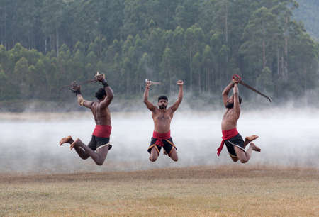 Indian fighters with swords jumping up during Kalaripayattu Marital art demonstration in Kerala, South Indiaの写真素材