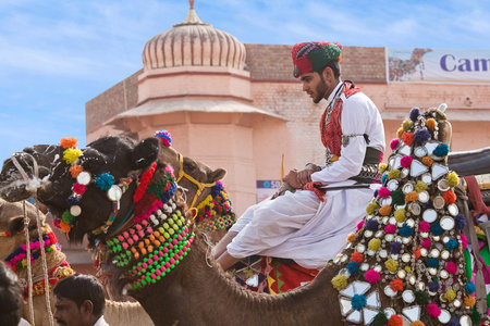 BIKANER, INDIA - JANUARY 12, 2019: Indian Rajasthani young man in traditional clothes riding on...