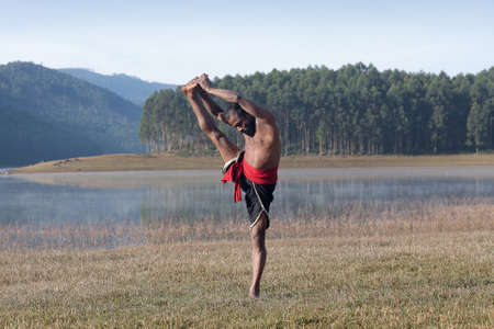 Indian man doing yoga exercises outdoors in Kerala state, South Indiaの写真素材