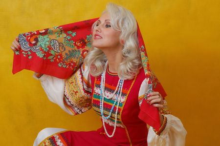 a beautifull woman in a folk russian dress on yellow backgroundの写真素材