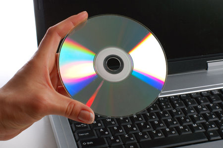 Close up. Woman with cd disk in a hand used notebook. White background