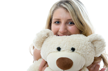 Happy little girl with teddy bear on a bedroom isolated on white backgroundの写真素材