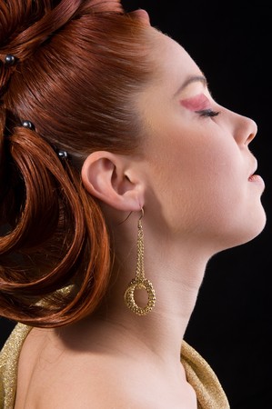 Close-up golden earring of a cute model with beautiful hair. Professional hairstyle.の写真素材