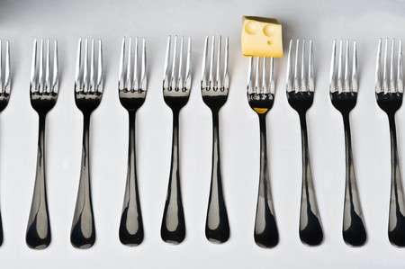 Row of the ten metal forks with one slice of cheese on gray backgroundの写真素材