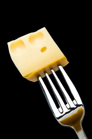Metallic fork with cheese on black background. path included.の写真素材