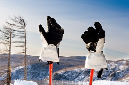 Gloves and ski sticks with mountains in the backgroundの写真素材