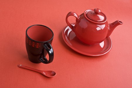 Teapot, cup and spoon on red tableの写真素材