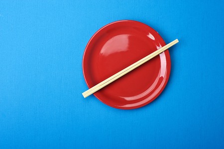 Red dish and chopsticks. Over blue tableの写真素材