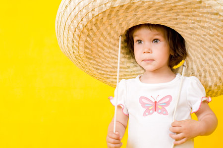 Little baby with big hat, Isolated on yellowの写真素材