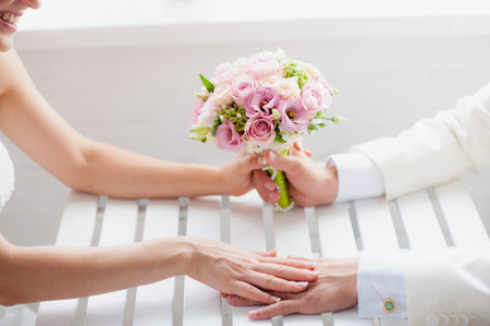 Bride and groom holding hands, sitting at the tableの写真素材