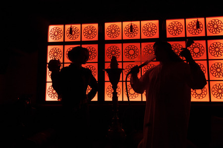 silhouette arab couple in the beautiful windows. Man holding a hookah and bellの写真素材