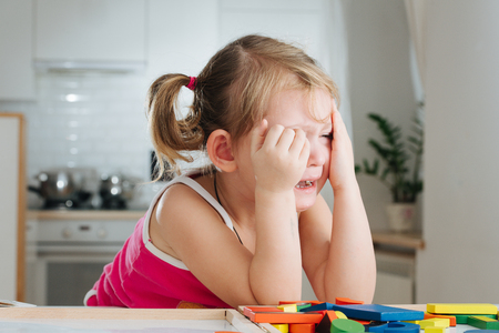 Charming preschooler playing with wooden constructor. Little girl playing with connecting piecesの写真素材