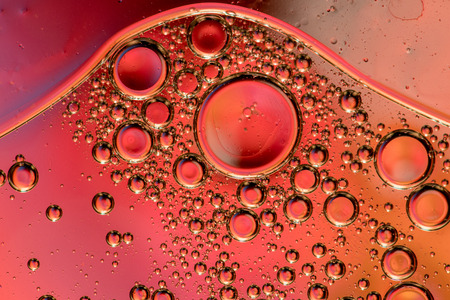 Macro shot of backlit liquid with small bubbles in it over colored background.の写真素材