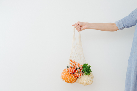 Closeup image, hand holding string bag with vegetables on a white backgroundの写真素材