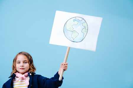 Little brunette girl holding planet earth sign in protest against pollution and waste crisis. Recycling and ecology.の写真素材