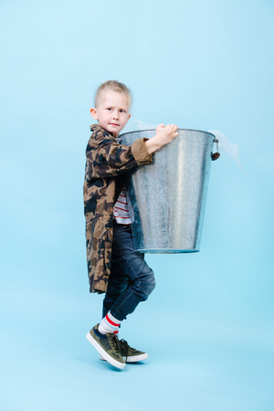Responsible little boy is carrying huge steel bucket with recyclable bubble wrap inside. Recycling and ecology.の写真素材