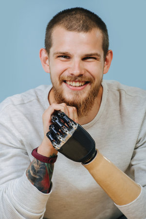 Portrait Of a smiling Man With Artificial hand in bright clothes sitting at the chair and looking at...