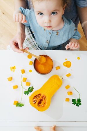 Close-up, top view. Mother feeds her daughter, eats mashed pumpkinの写真素材