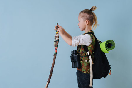Little boy playing hiker at home. Hes working on his hiking stick. Over blue.の写真素材