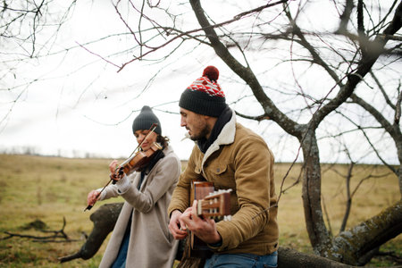 Two musicians sitting on a branch, playing music in a autumn countryside
