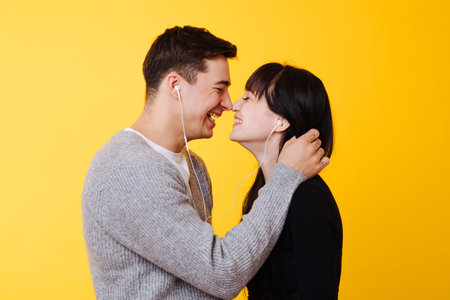 Young happy couple in love about to kiss, they are touching noses while listening to the music over...