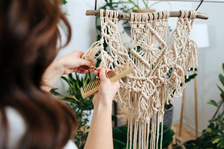 Craftswoman working out last details of an almost-finished macrame piece