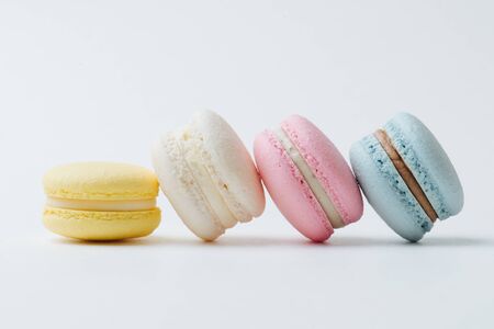 Close up image of multi-colored macarons arranged in a row with each next cake leaning on the other. They are made of almond flour with cream. Exquisite delicacy in desserts.の写真素材