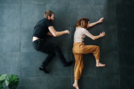 Man and woman depict running while lying on the floor. He's chasing her.の写真素材