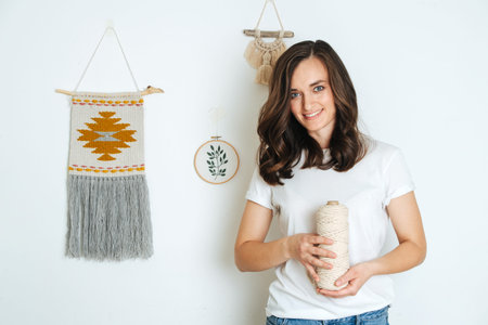 Portrait of a professional girl in macrame weaving, against the background of her works.