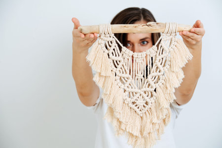 The art of weaving knots of thick twisted threads, a product made in the technique of macrame. Girl shows macrameの写真素材