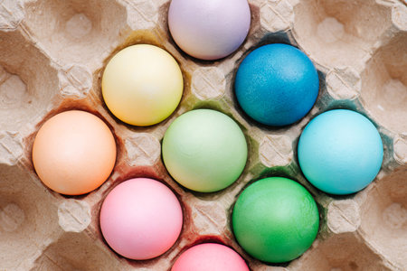 Colorful easter eggs in a cardboard egg case. Close up. Top view.