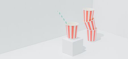 Disposable, compostable, recyclable striped paper buckets for soda in the corner over white background. Straw in one of the cups.の写真素材