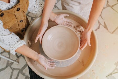 close-up of children's palms behind the potter's wheel. Two children forming a bowlの写真素材