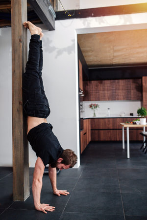 Sports exercises at home, the men performs a handstand. Quarantine concept, domestic life in...