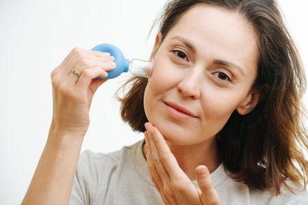 Taking care of the face skin. A young woman does herself a face massage using special cosmetic...